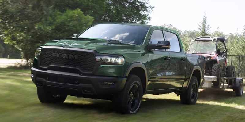 Ram pickup towing an off-road vehicle trailer.
